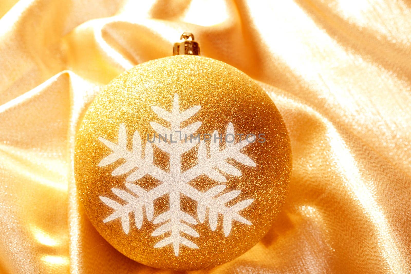 Christmas glitter snowflake bauble on golden fabric background