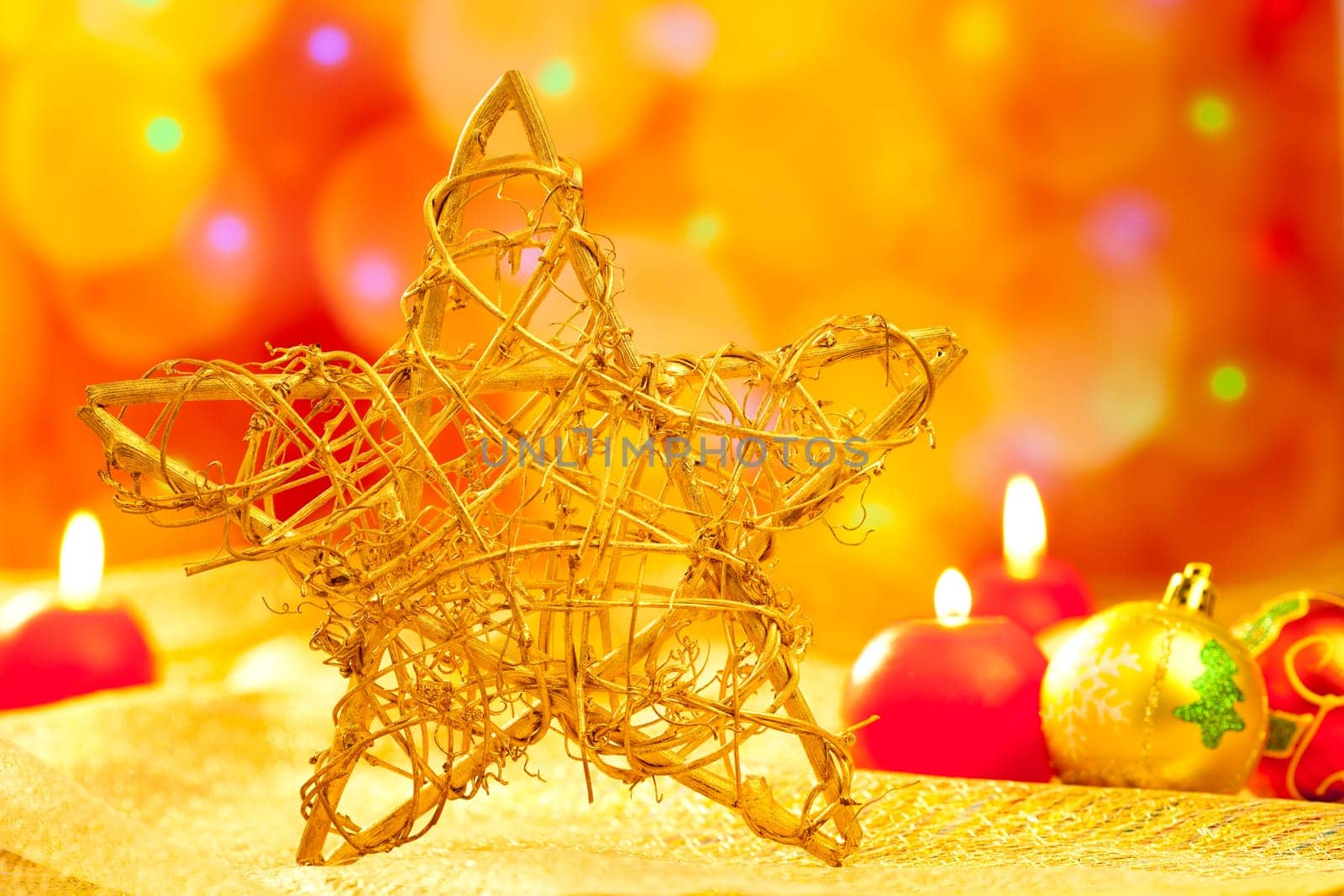 Christmas golden branch star with candles and baubles in blurred lights