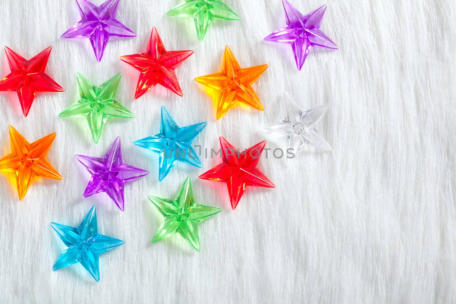 christmas colorful glass stars over white fur background as snow