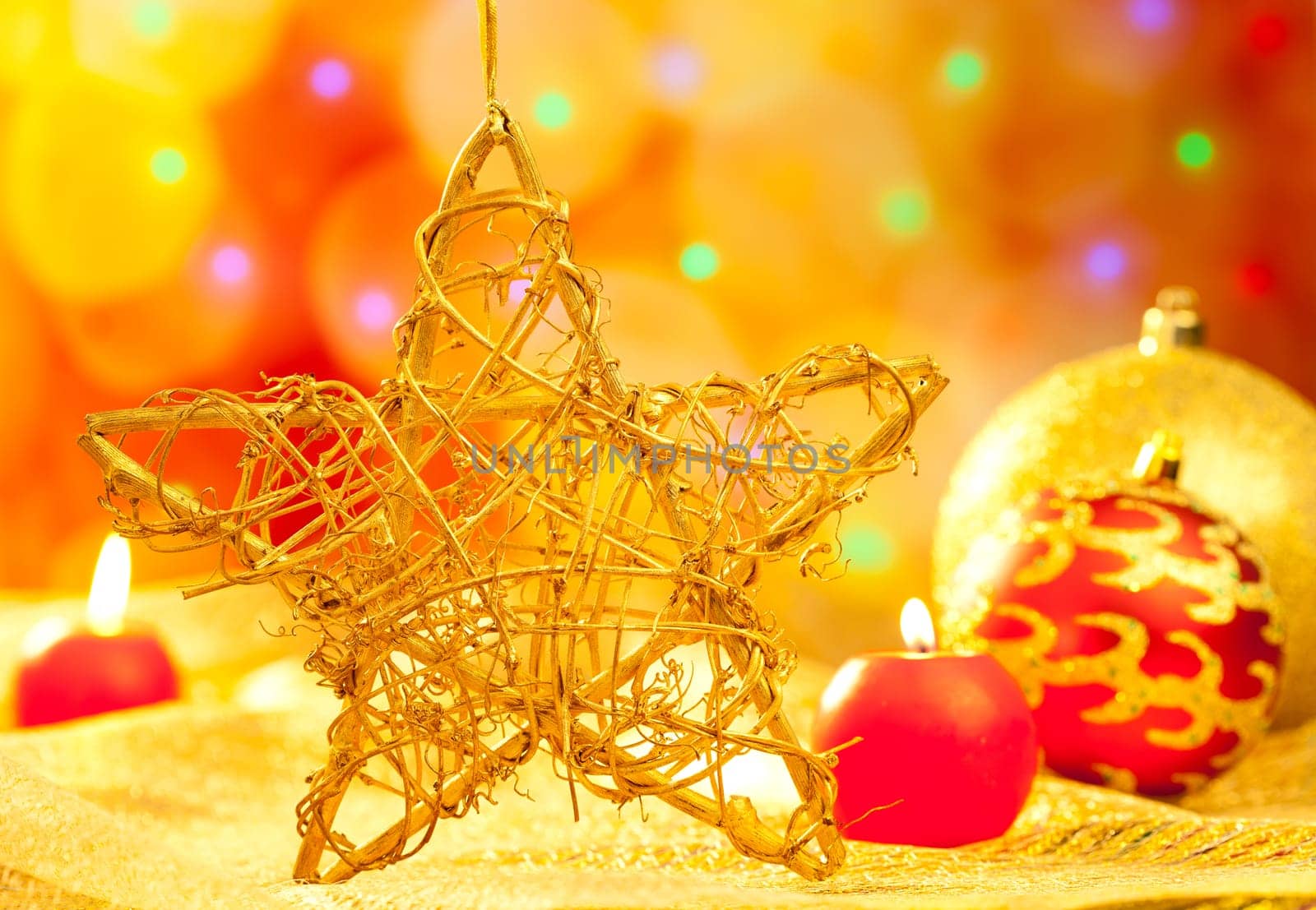 Christmas golden branch star with candles and baubles in blurred lights