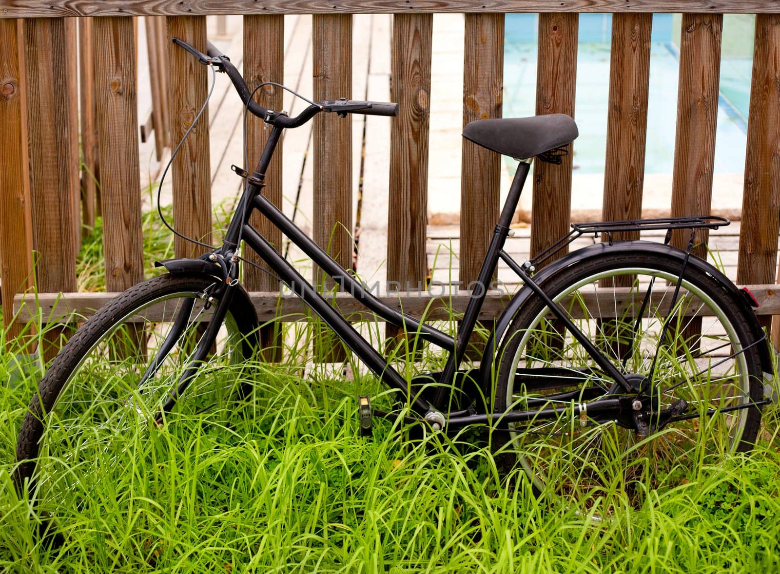 black grunge bicycle aged on a wood fence and grass
