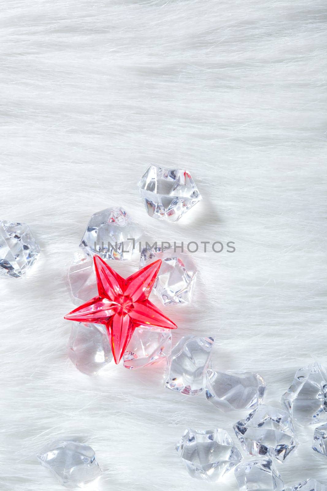 christmas red crystal star over ice cubes and white fur background
