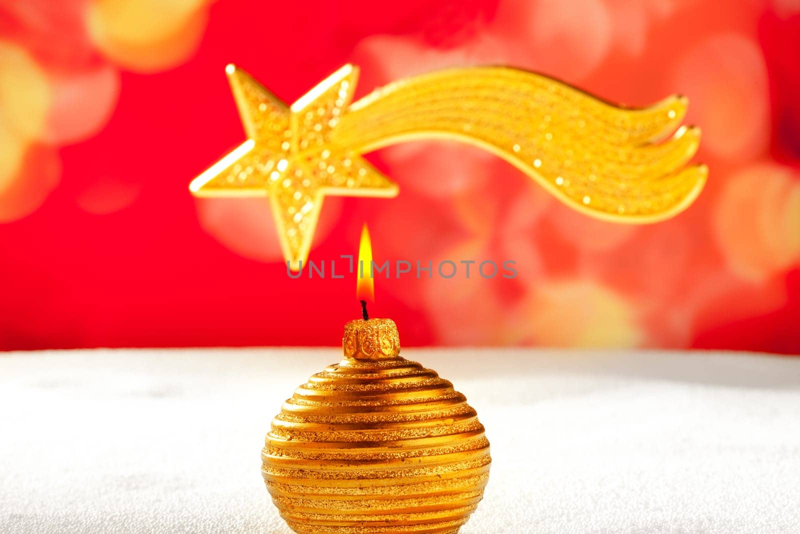 Christmas golden candle and bethlehem comet star on snow and red
