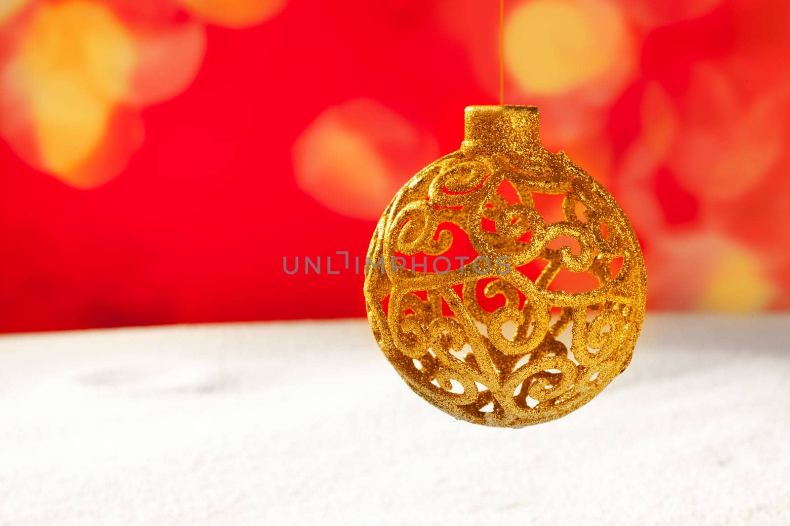 Arabesque christmas golden bauble on snow and red bokeh background