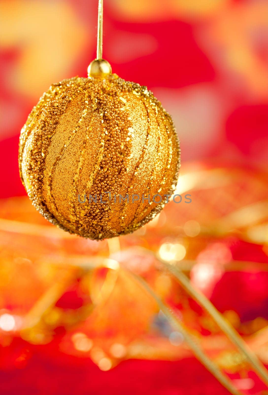 Christmas card of golden bauble and red blur background