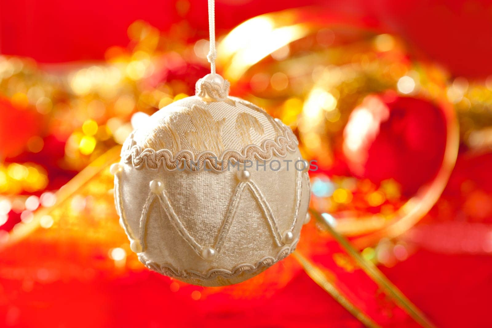 Christmas card of white velvet bauble and red blur background