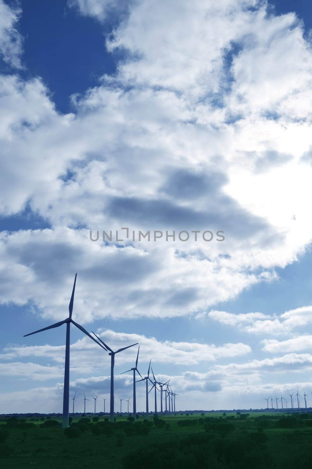 Ecological electric energy production by windmills in a meadow and blue sky