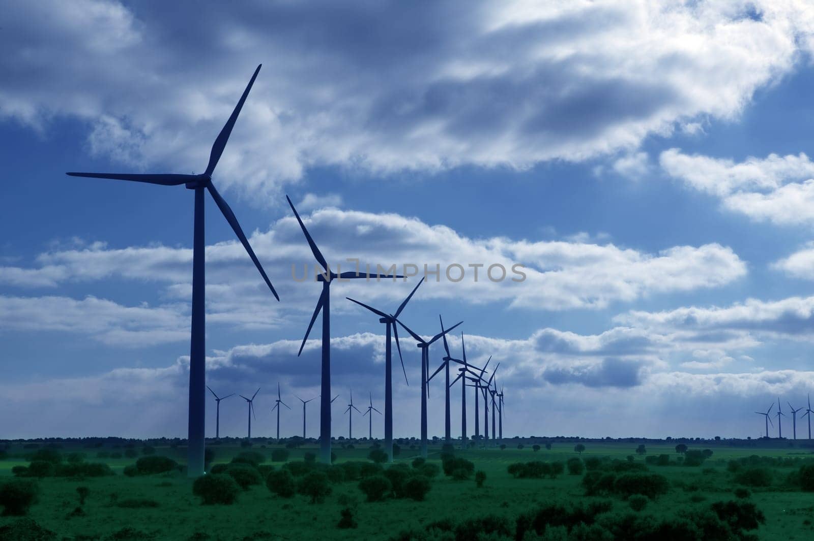 Ecological electric energy production by windmills in a meadow and blue sky