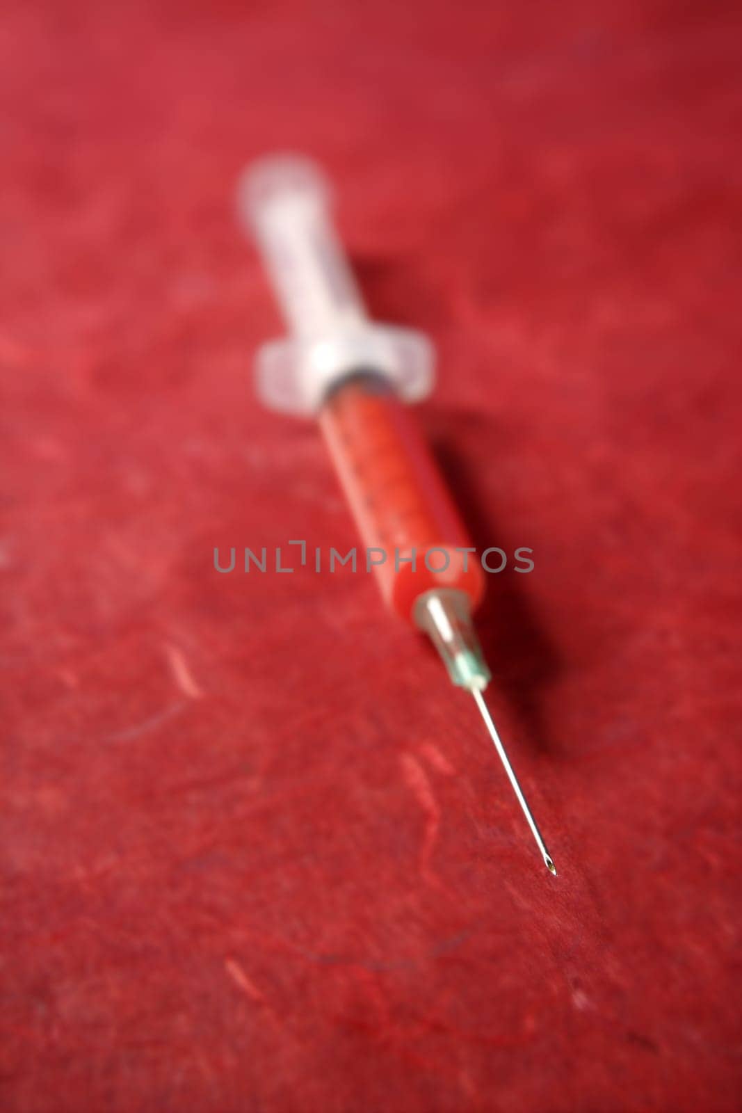 health red syringe vertical over red background