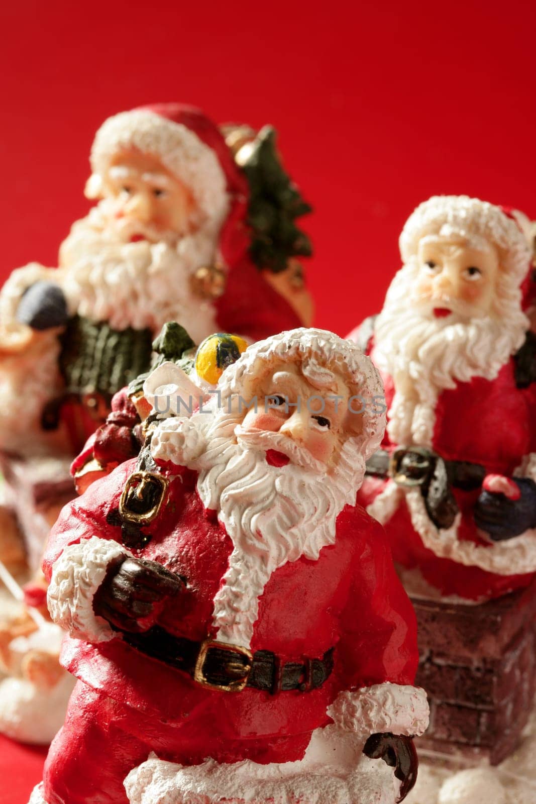 Three Santa Claus figurines over red background, studio shot