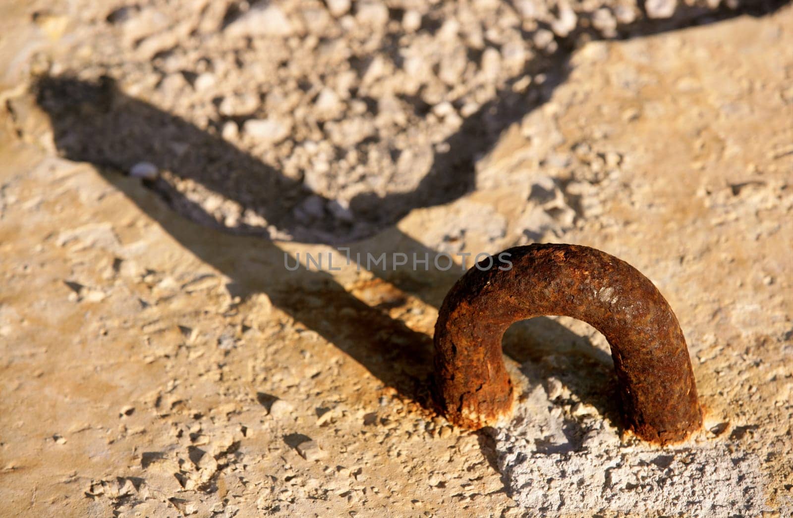 aged rusty shackle in dock concrete stone, with long shadow