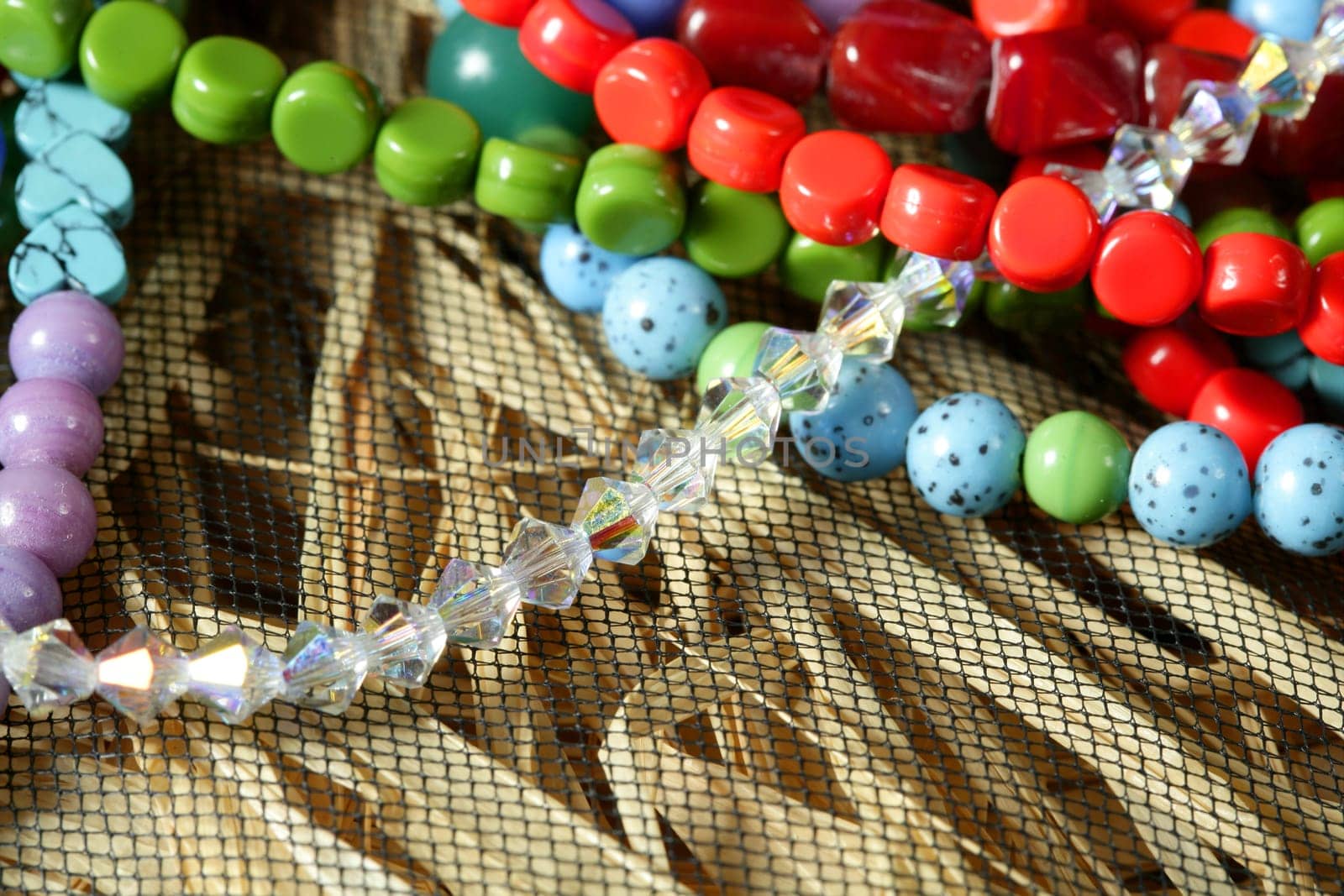 Color stones jewelry necklaces over natural straw and tulle background