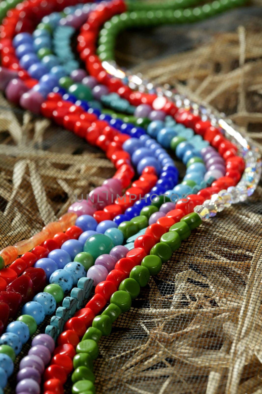 Color stones jewelry necklaces over natural straw and tulle background