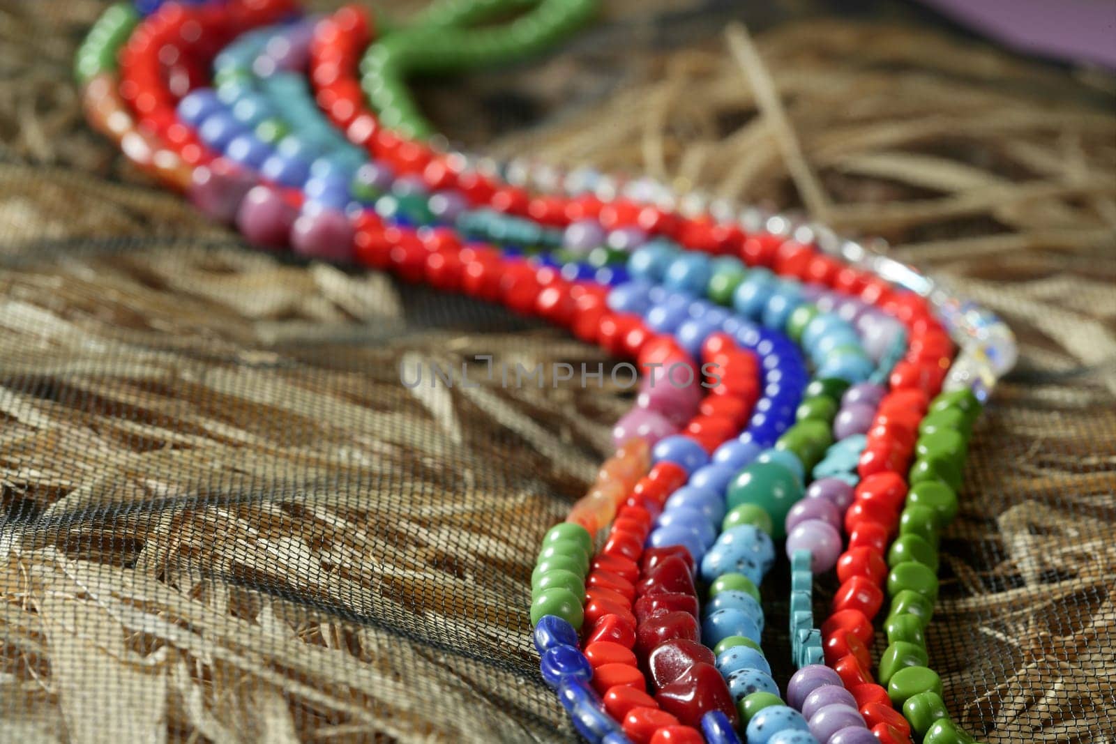 Color stones jewelry necklaces over natural straw and tulle background
