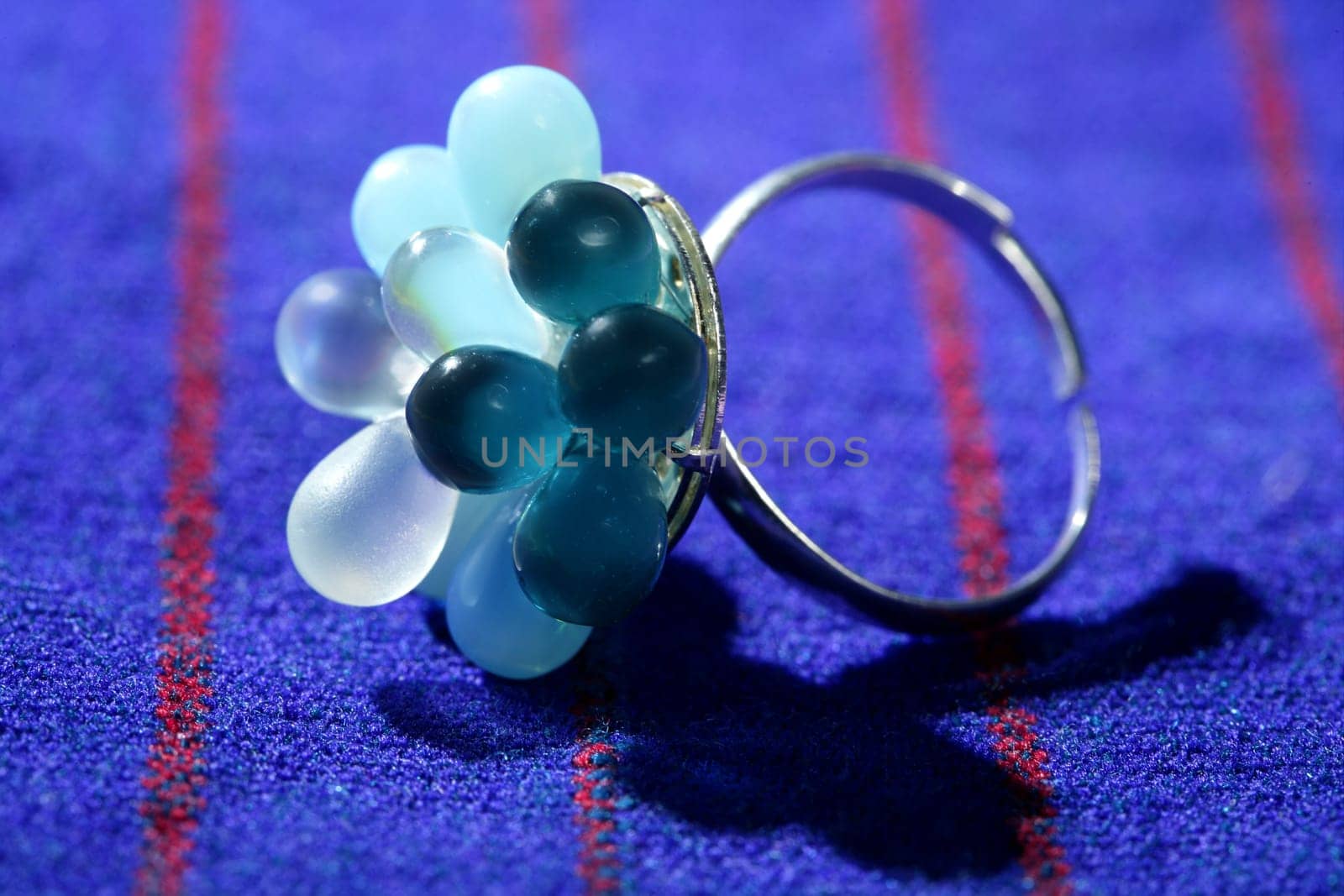Colorful gem stones silver ring over vivid fabric background