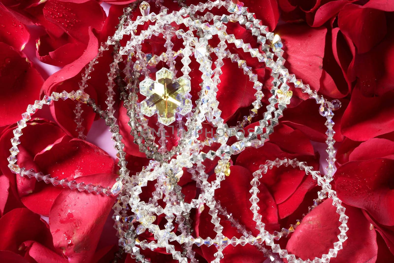 Shiny jewelry over bed or red rose petals