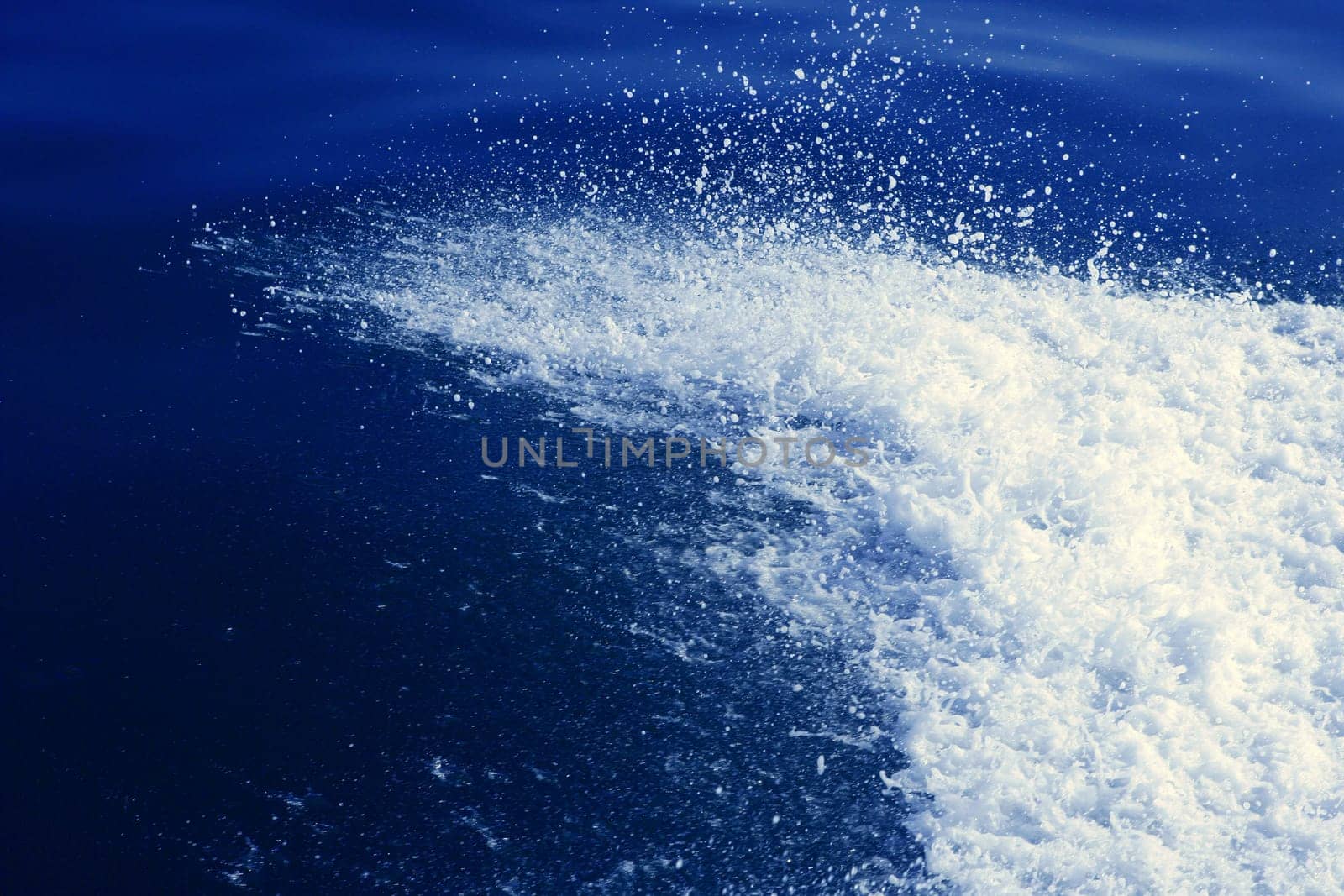 Water splash at the starboard boat side on blue ocean sea