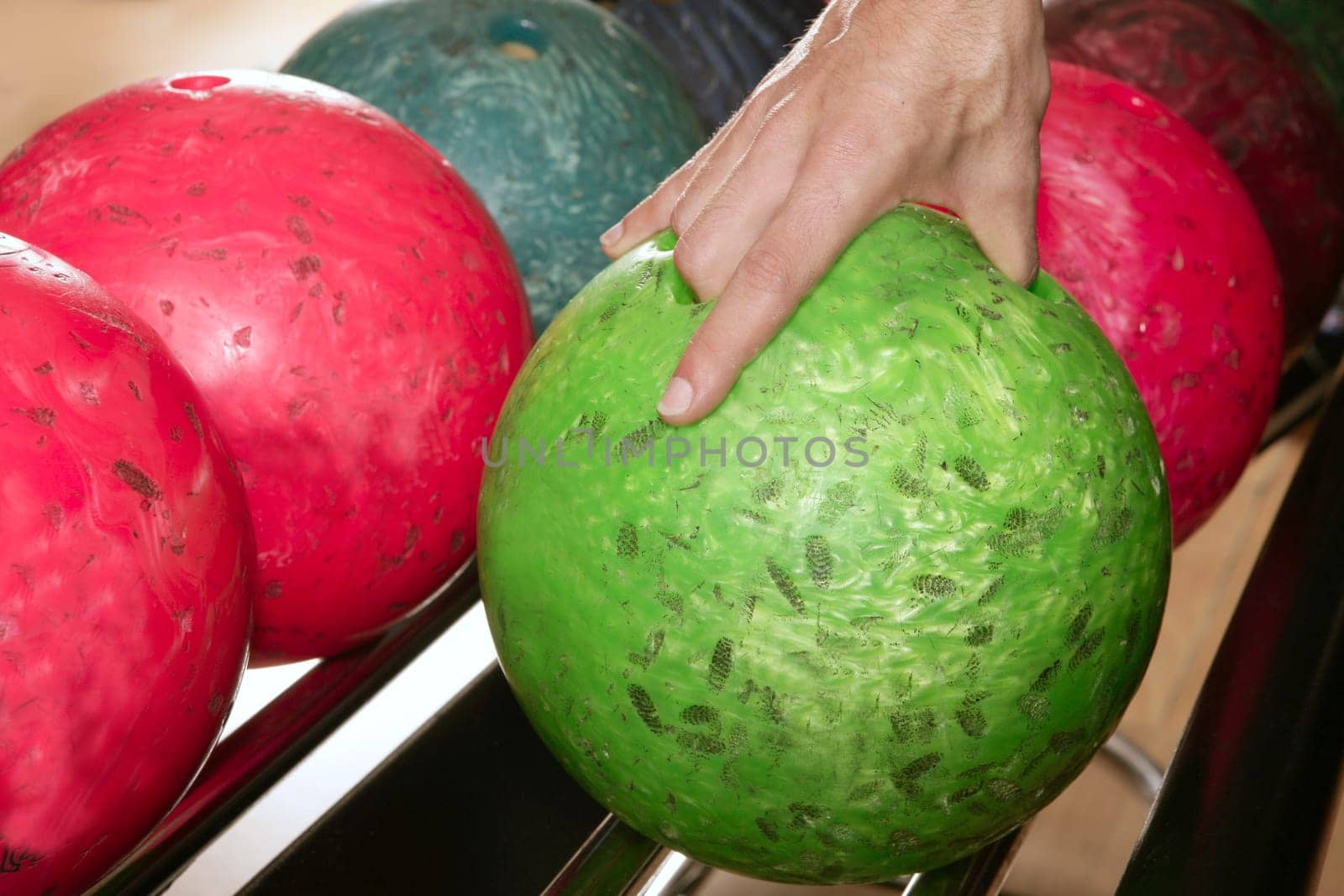 Bowling ball in player man hand in colorful rows
