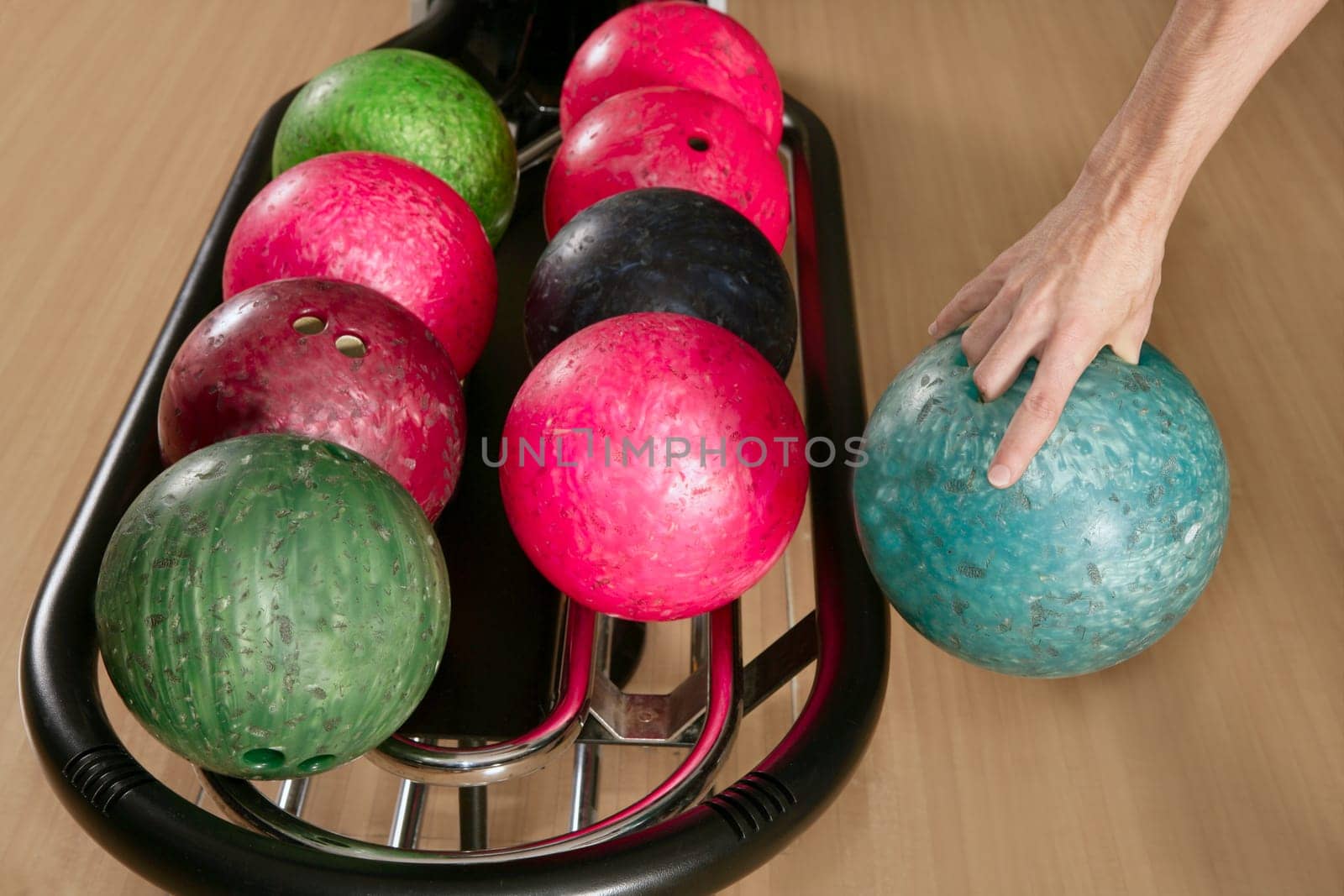 Bowling ball in player man hand in colorful rows