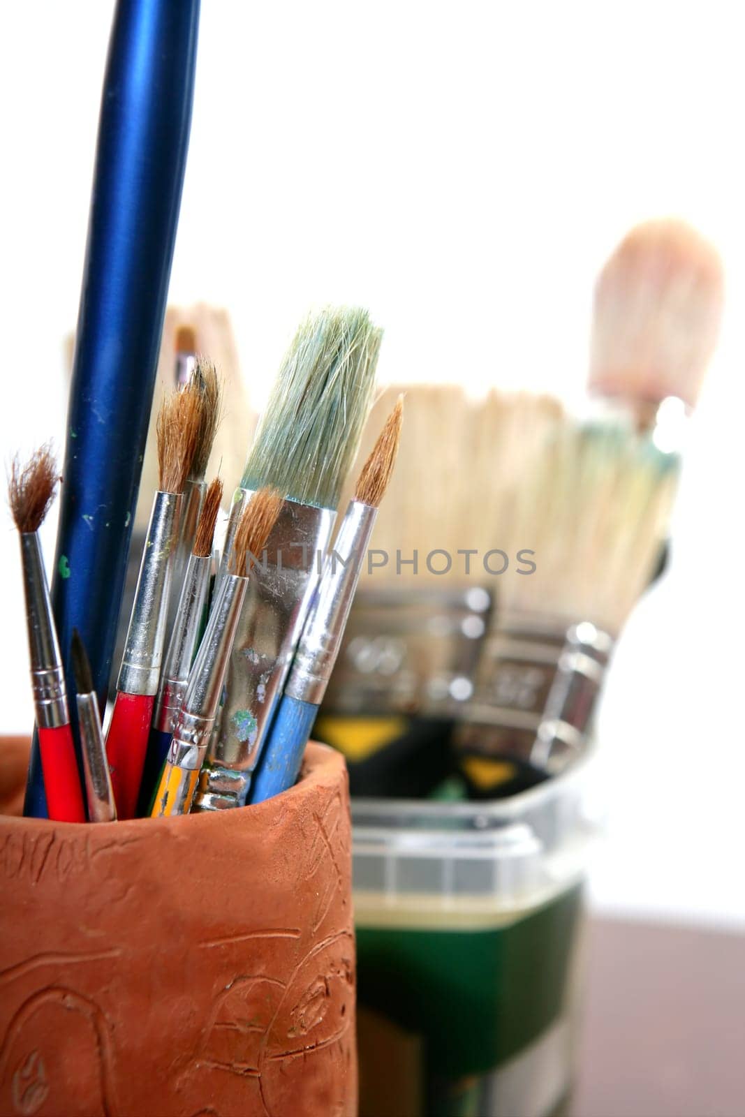 Artist used brushes clay pot isolated on white