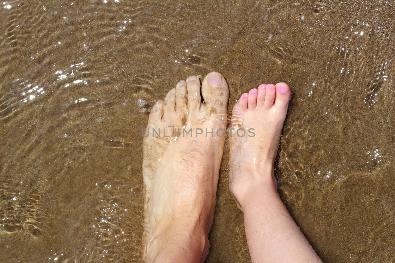 father and children feet on summer sand beach shore wavy water