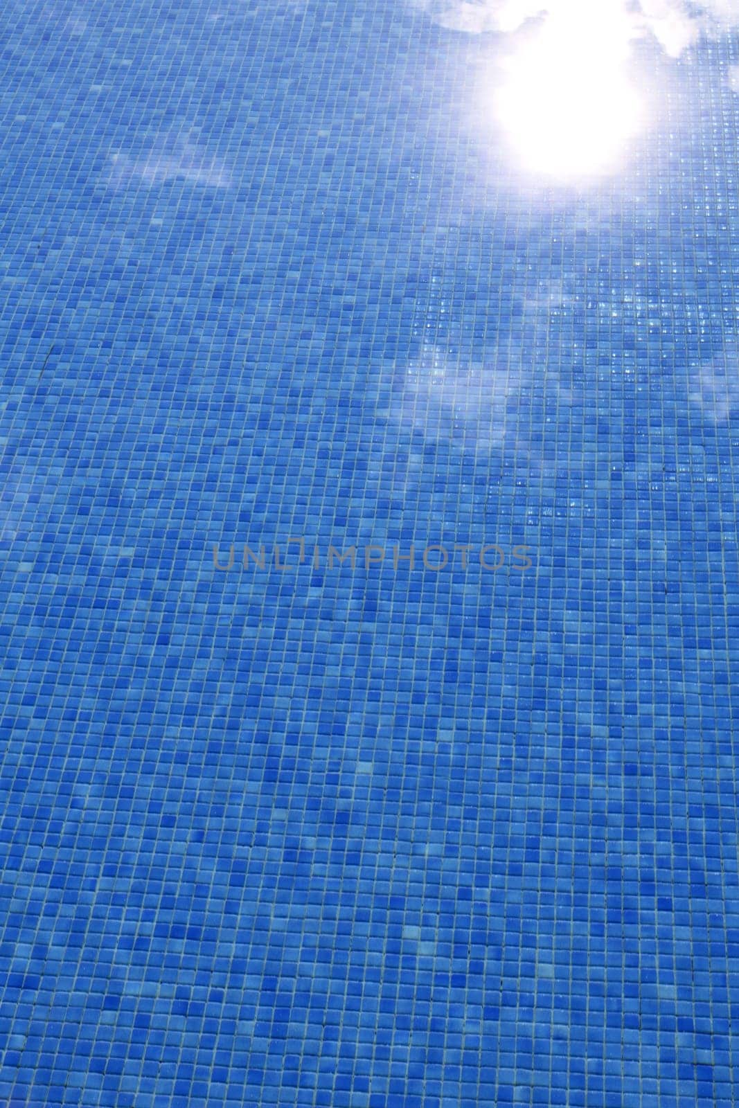 blue tiled swimming pool with sun reflexion summer vacation background