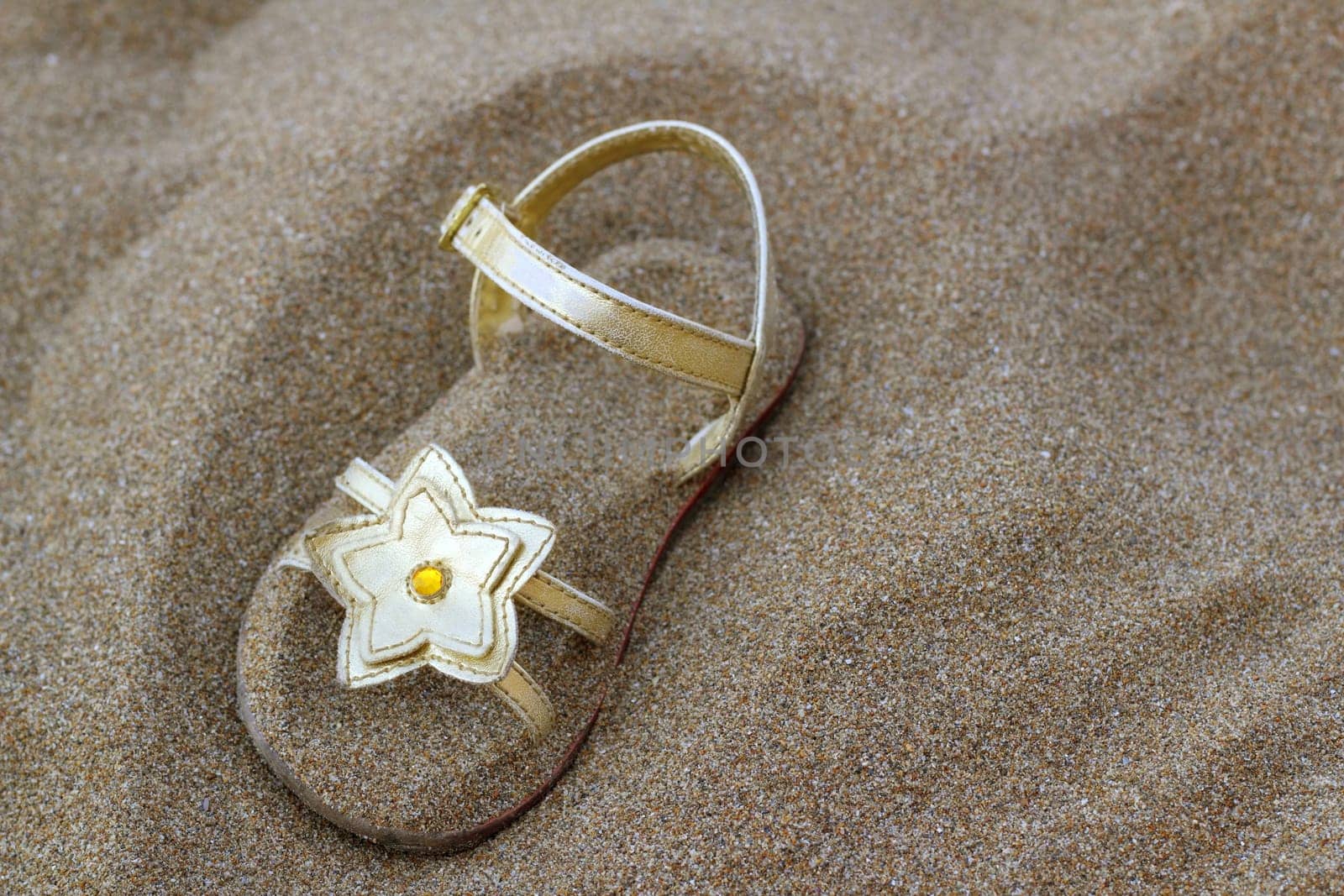 golden star sandal buried in summer beach sand vacation metaphor