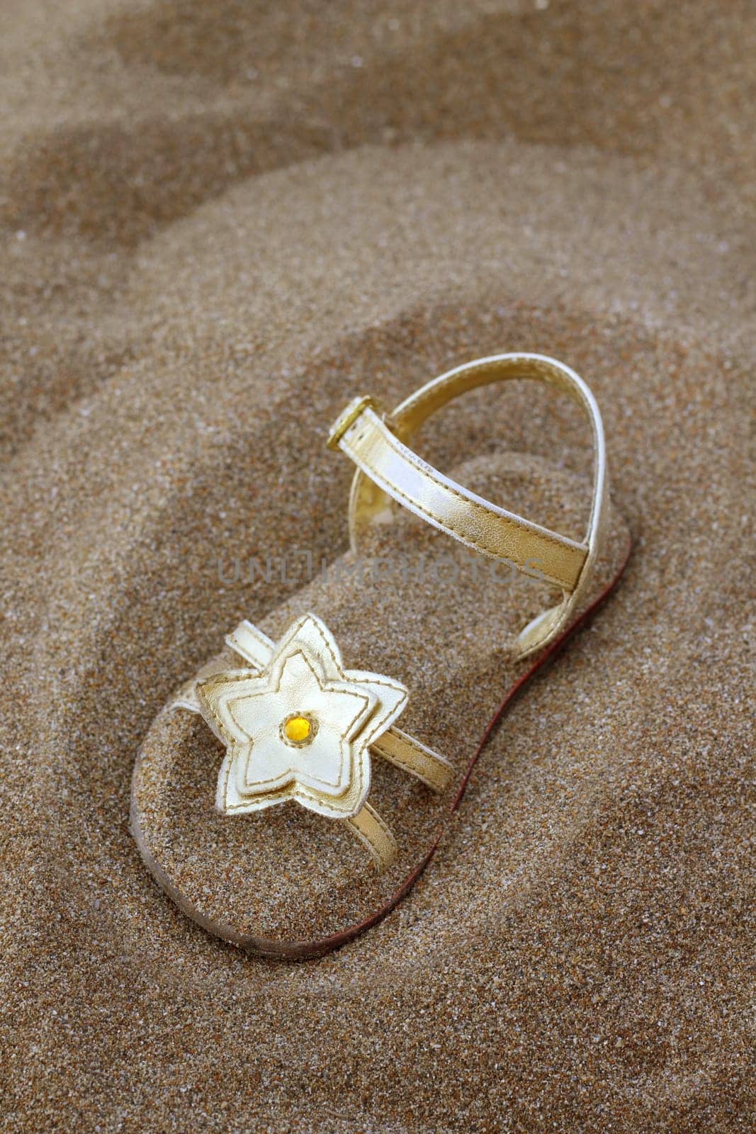 golden star sandal buried in summer beach sand vacation metaphor
