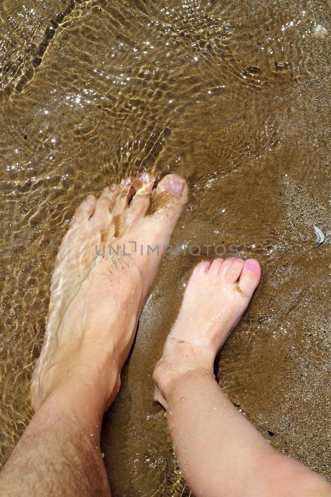 father and children feet on summer sand beach shore wavy water