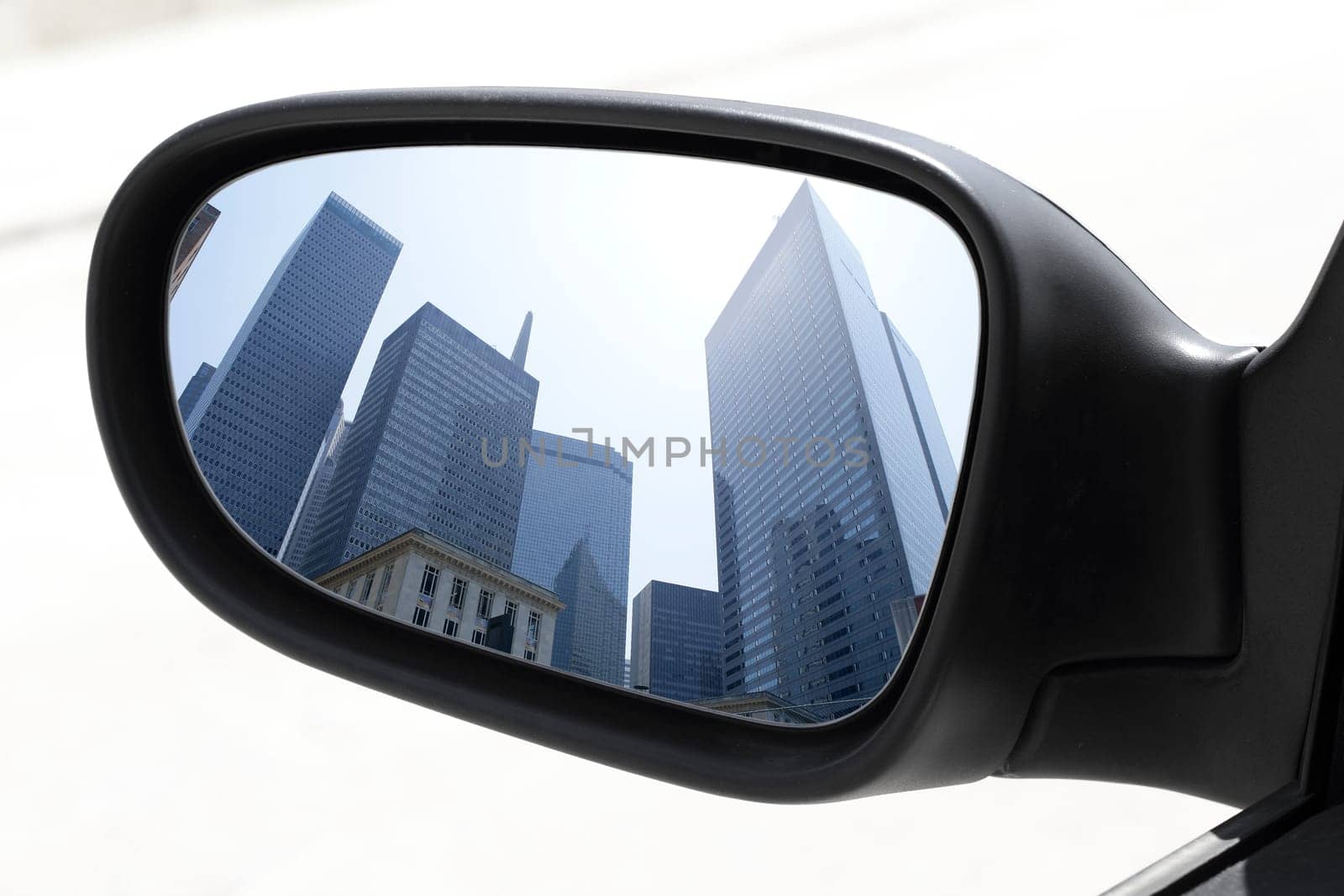 rearview car driving mirror view skyscraper city downtown buildings