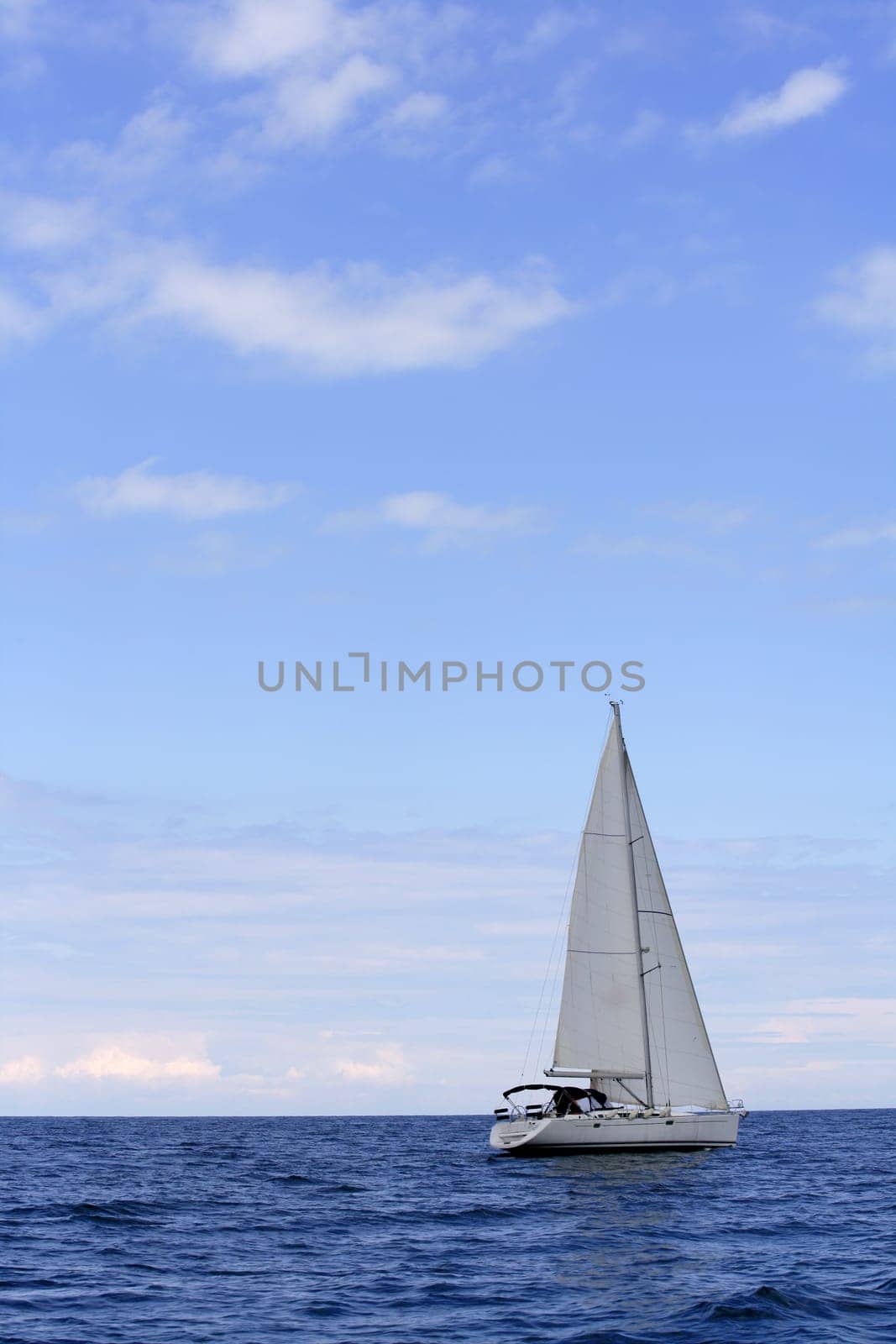 Blue sea with sailboat sailing the ocean surface