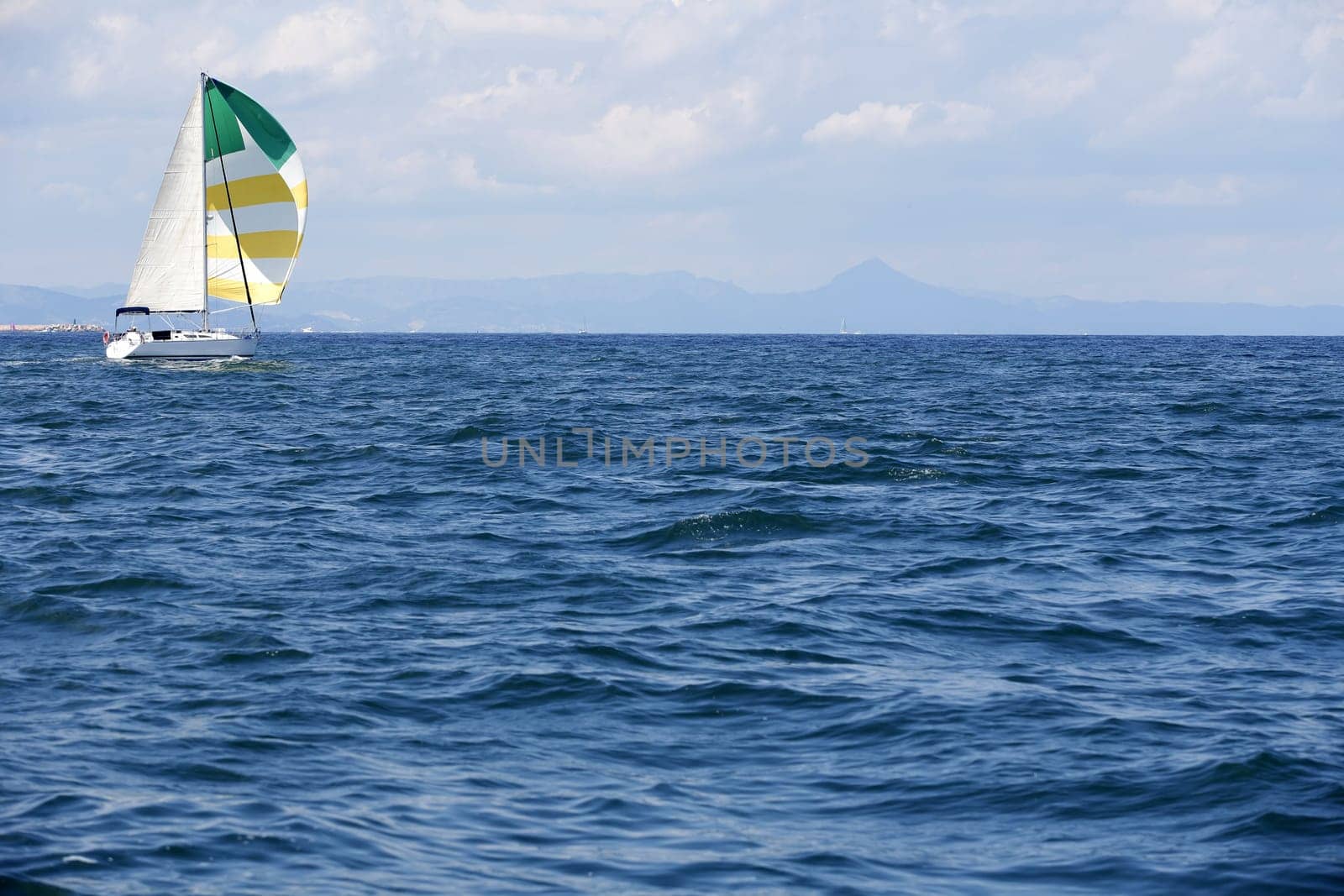 Blue sea with sailboat sailing the ocean surface