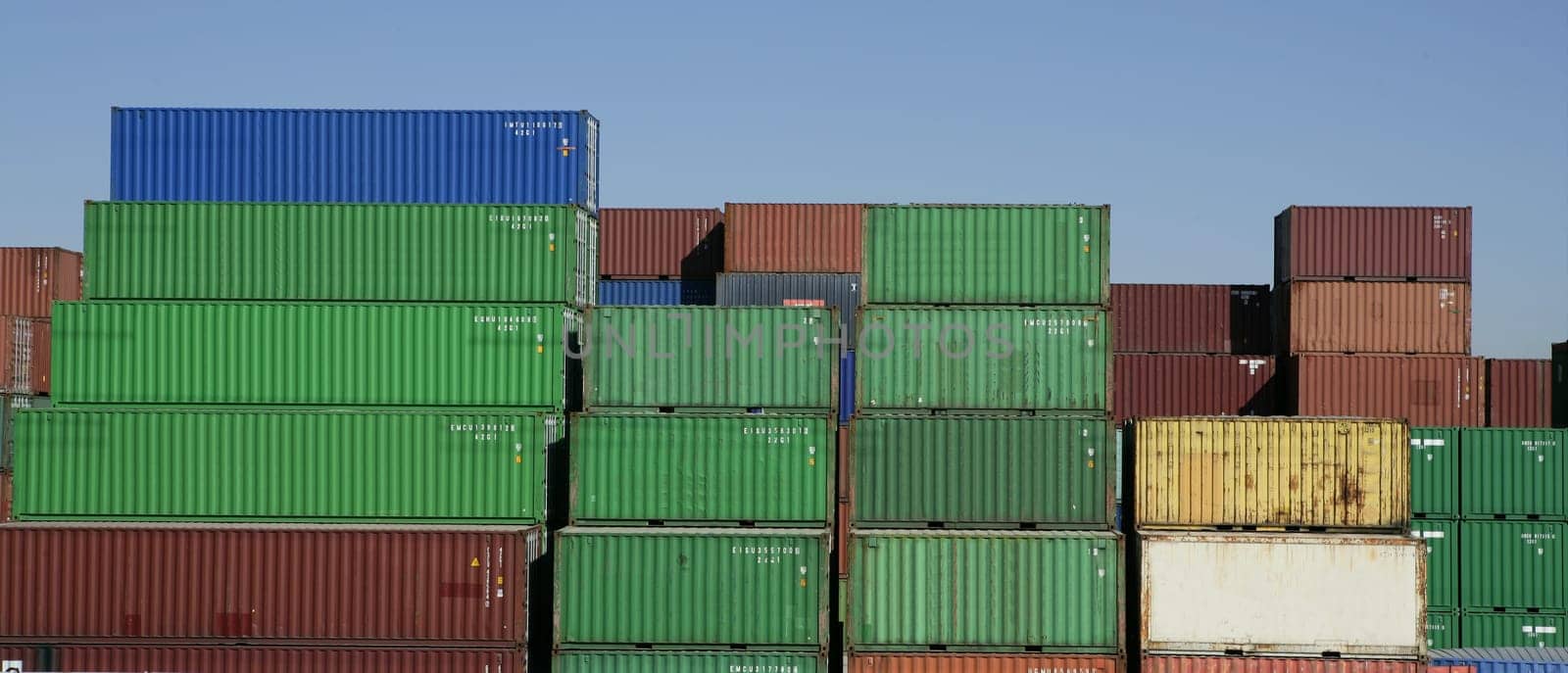 Stacked freight colorful containers on harbour, blue sky