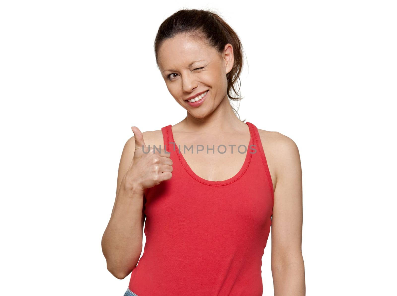 Portrait of cute expressive woman winking and gesturing thumbs up in studio on isolated white background