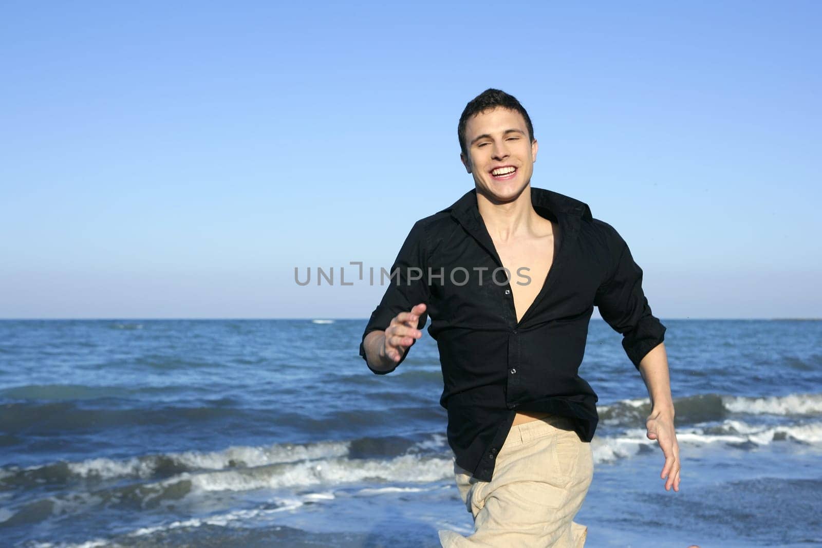 Man running happy on the blue summer beach, sunny summer