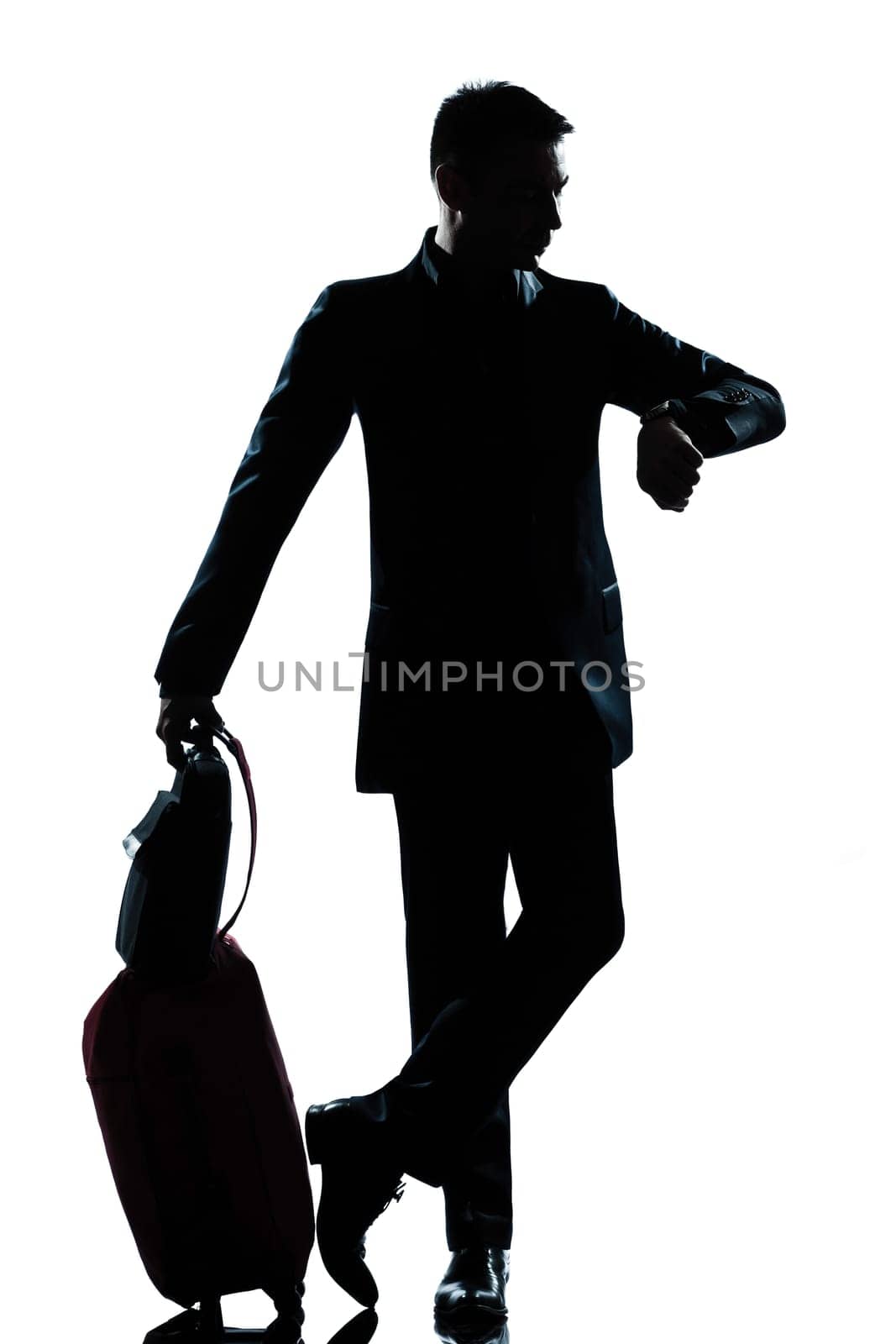 one caucasian  business traveler man checking the time full length silhouette in studio isolated on white background