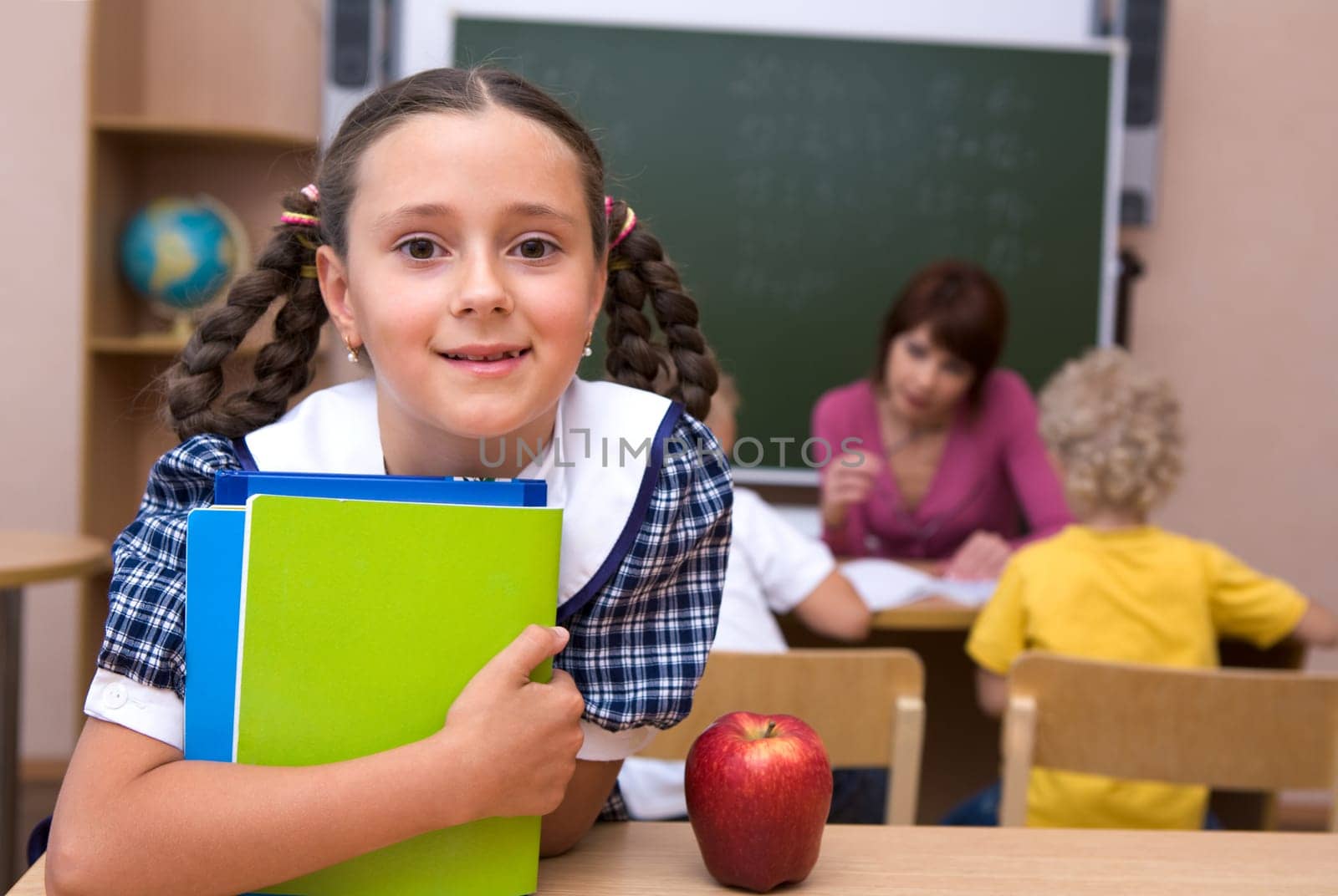 Portrait of happy girl with copybooks looking at camera at school