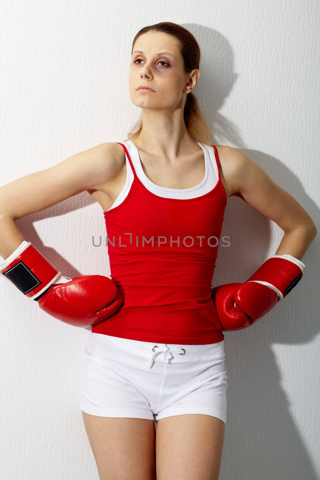 Portrait of young sporty woman in red boxing gloves looking aside