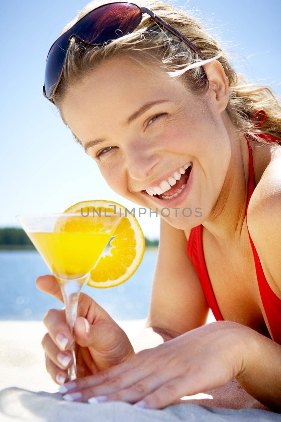 Portrait of relaxing woman lying on sand with cocktail