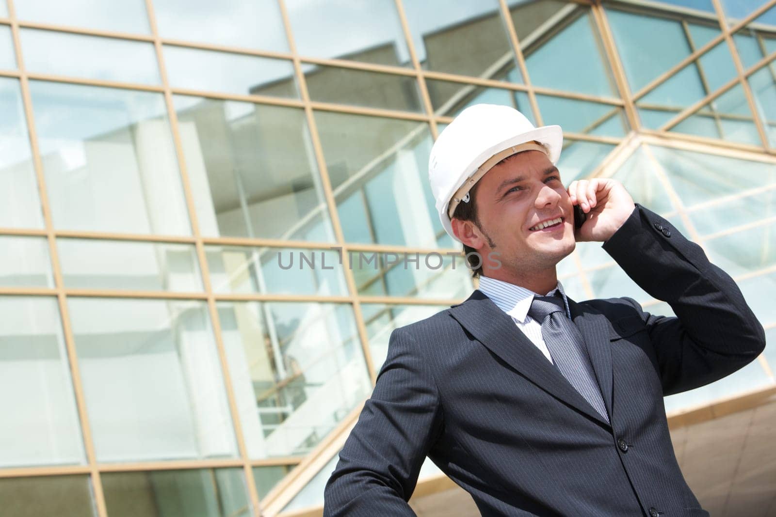 Portrait of confident foreman in helmet calling by mobile phone