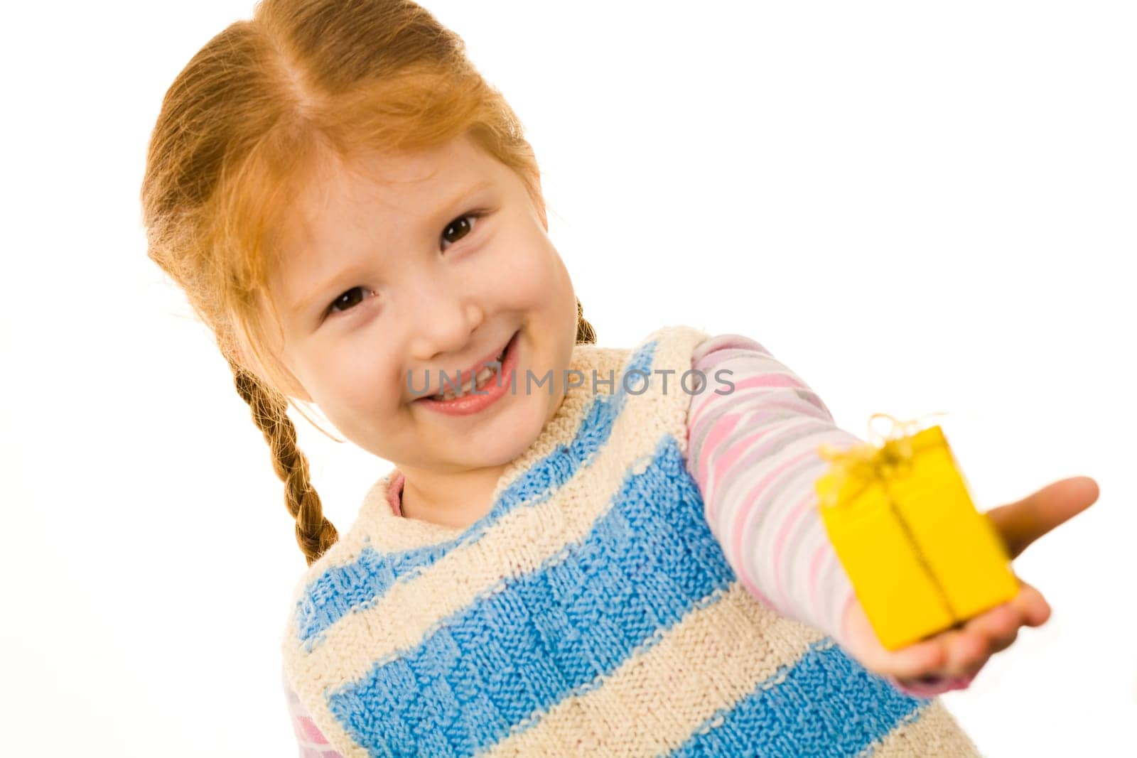 Little redheaded girl giving somebody small present in yellow box and smiling