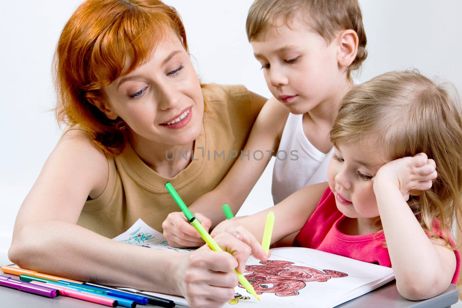 Pretty mother, her smart son and daughter are drawing the picture together