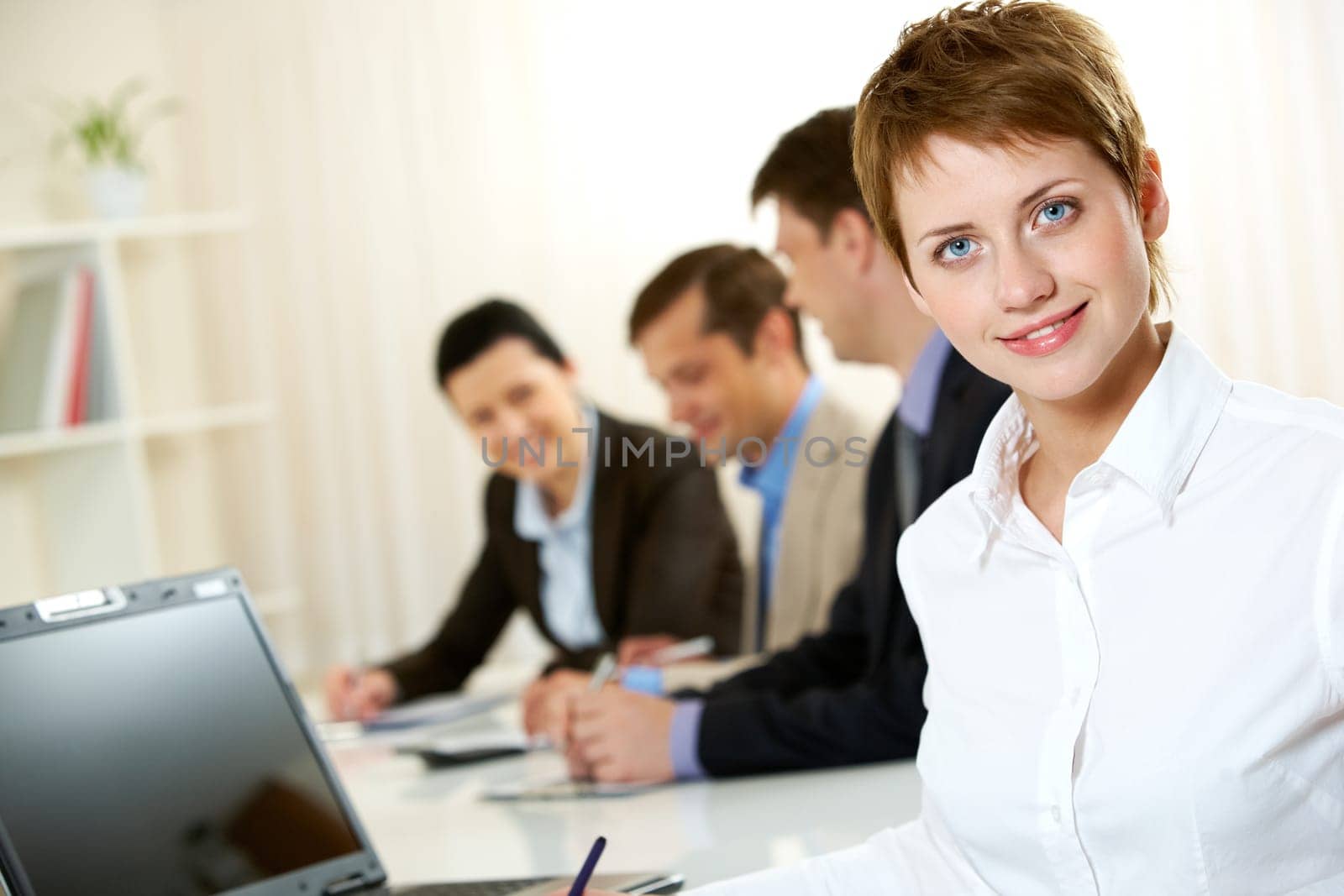Row of businesspeople in board room, the focus is on young woman