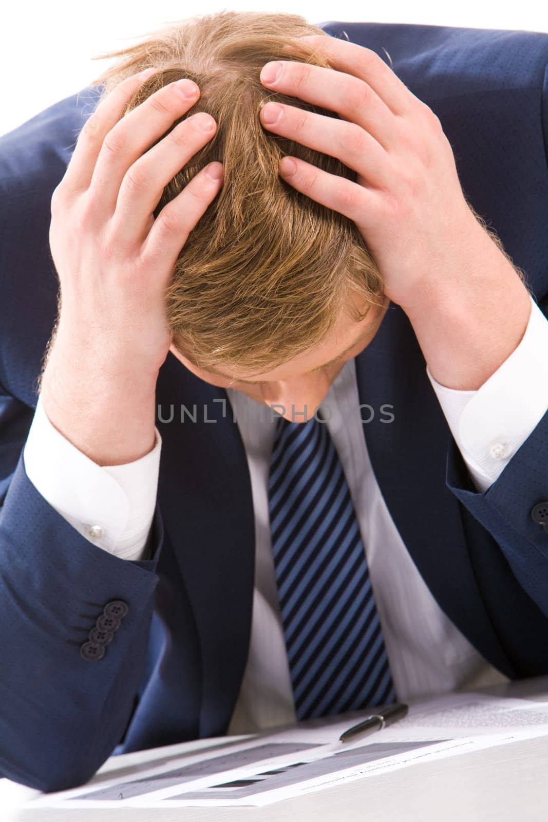 Portrait of tired businessman touching his head while doing paperwork
