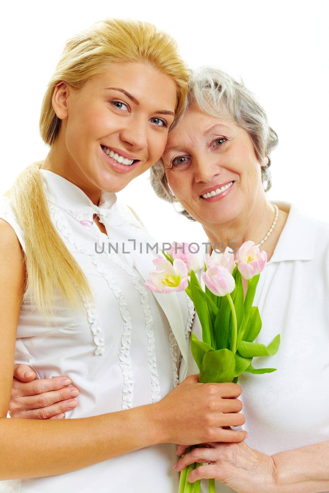 Portrait of pretty woman embracing her senior mother and holding tulips