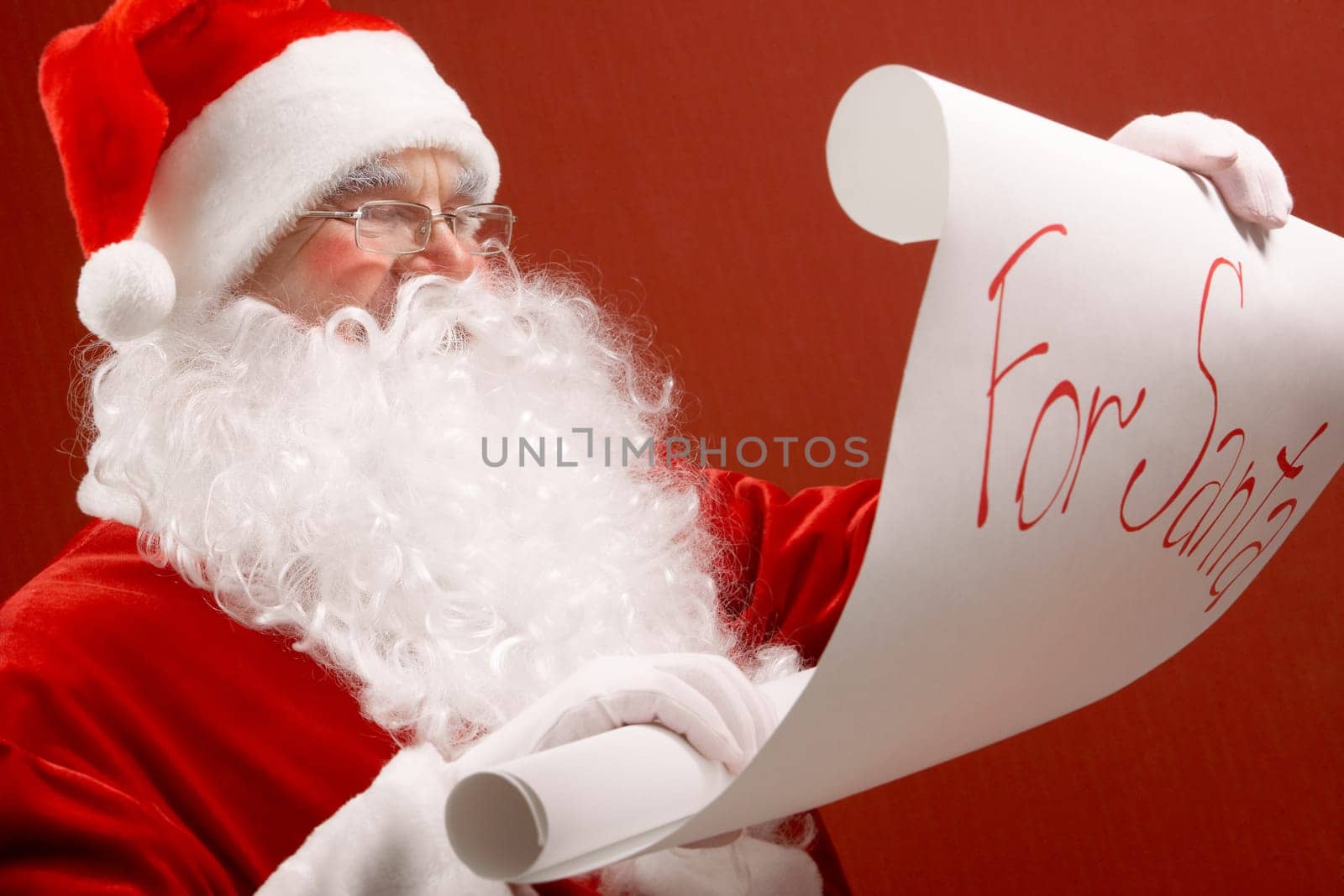 Portrait of cute Santa Claus reading big letter on red background