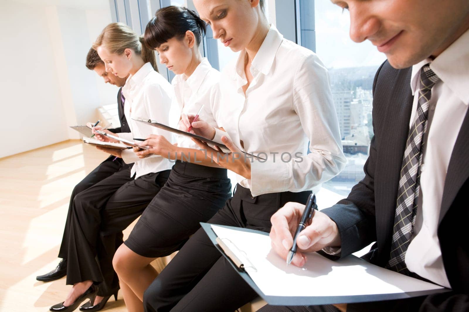 Image of row of business people writing on papers at seminar