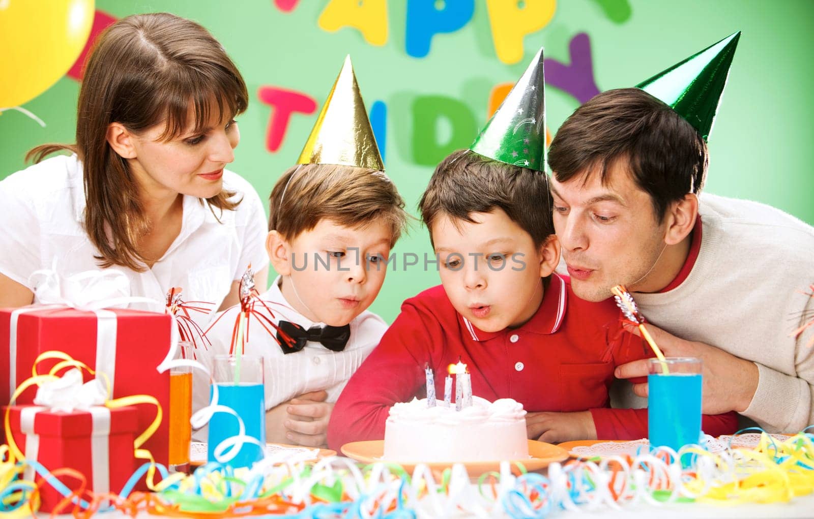 Portrait of family blowing together at the holiday candles on the cake