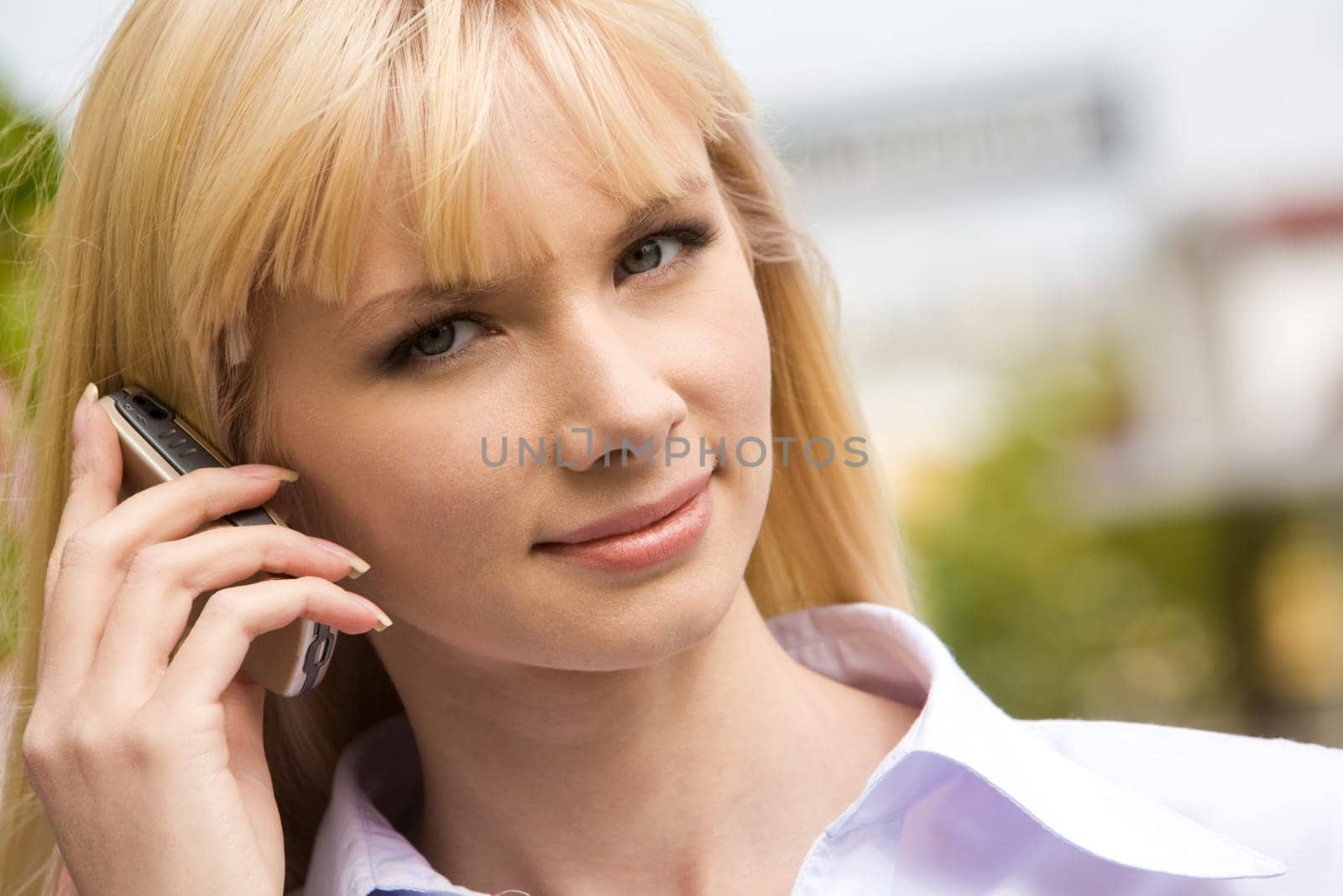 Portrait of modern female holding cell by her ear and looking at camera