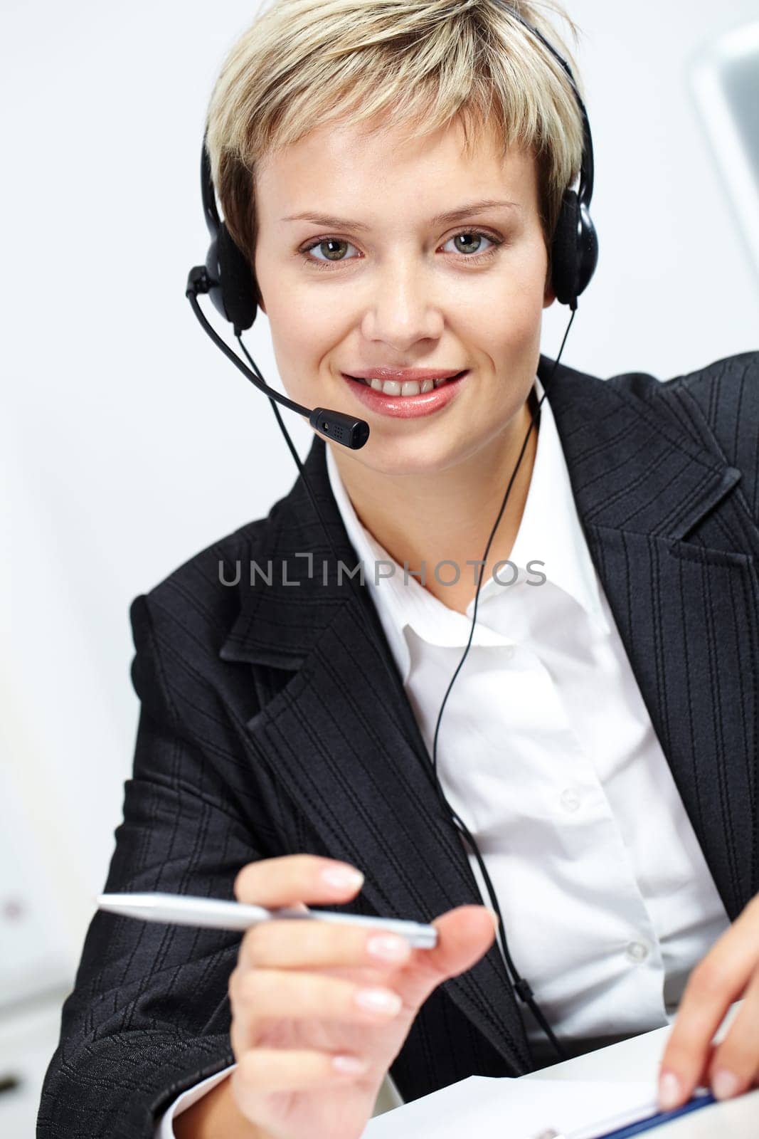 Portrait of young attractive secretary with headset looking at camera and smiling